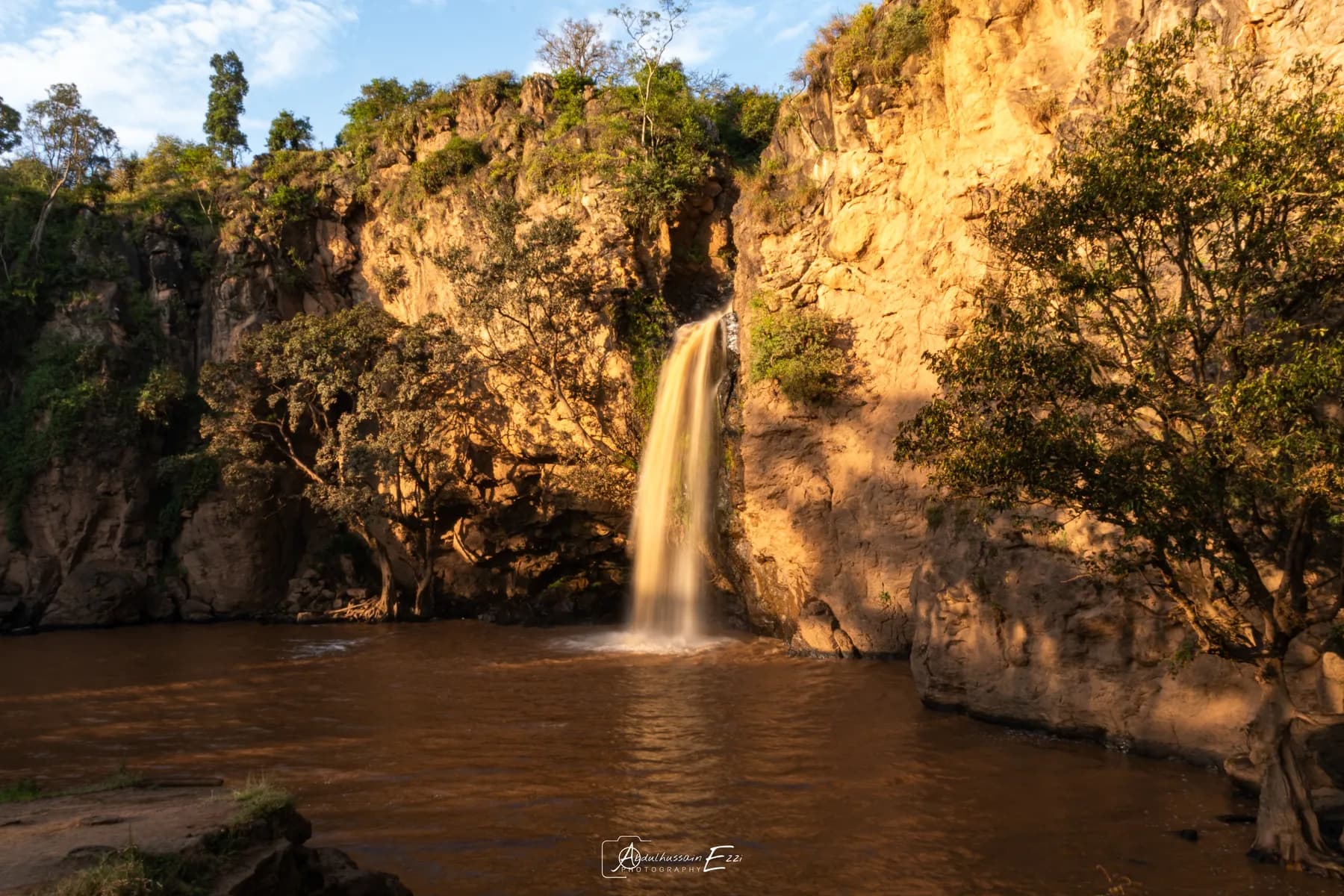 A waterfall pouring over golden cliffs in Lake Nakuru National Park